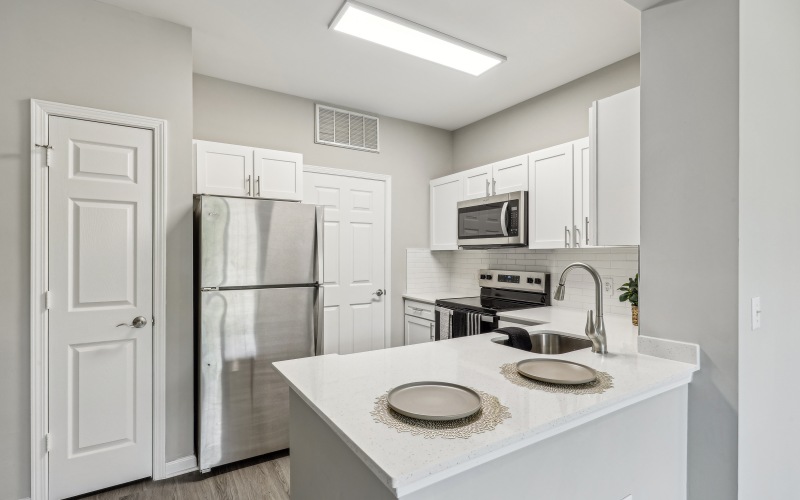 Newly renovated apartment home with white countertops, cabinets, and stainless steel appliances